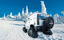 Белый Hummer H2 на гусеницах поднимается на снежную гору